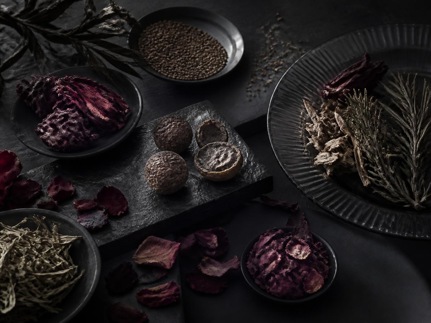 Flat lay of amla, hibiscus, rose petals, rosemary, fenugreek and neem on ivory linen
